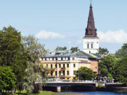 Karlstad sett från Älven med historiska byggnader och ett högt kyrktorn som reser sig över staden.