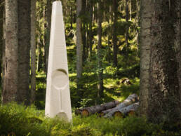 En konstinstallation i den värmländska skogen, omgiven av stora och höga granar.
